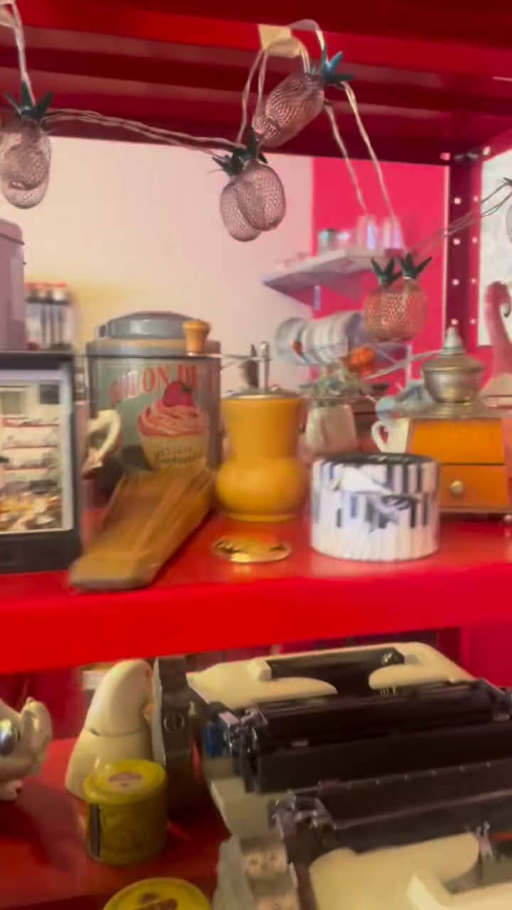 Moedores de café antigos de madeira e latas na prateleira vermelha.